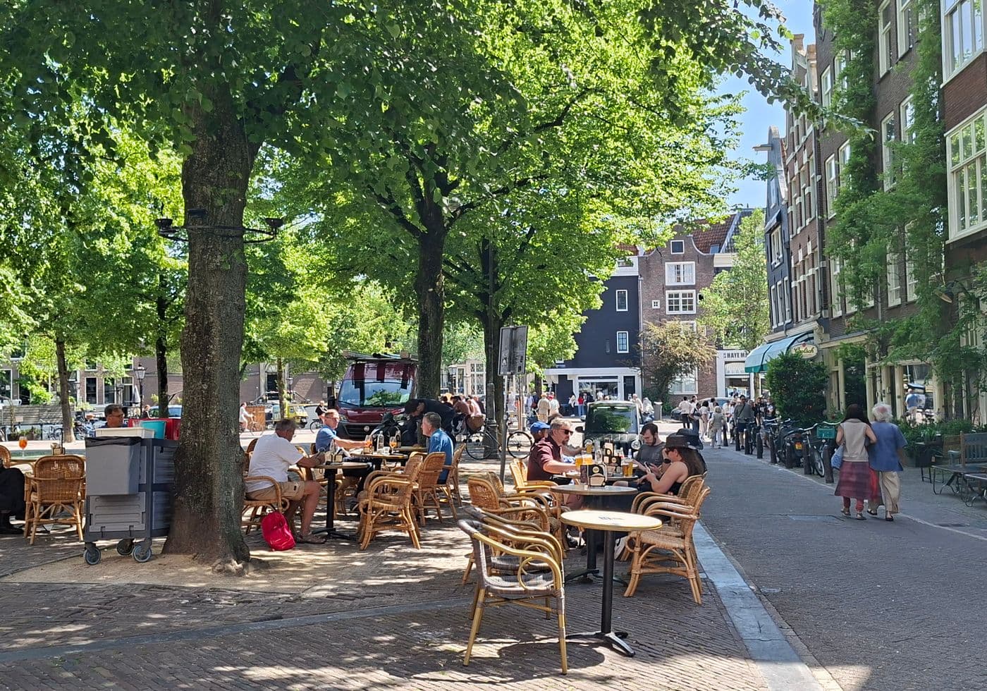Terrasgasten onder de bomen bij een horecazaak